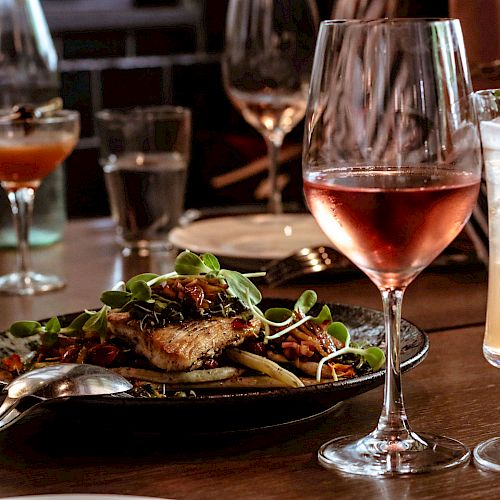 A table setting with various drinks and a plated dish, featuring glassware and cutlery, suggesting a dining experience.